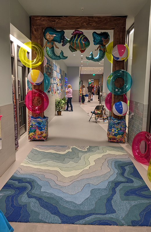 A hallway decorated with inflatable mermaids, beach balls, and colorful tubes A hallway decorated with inflatable mermaids, beach balls, and colorful tubes