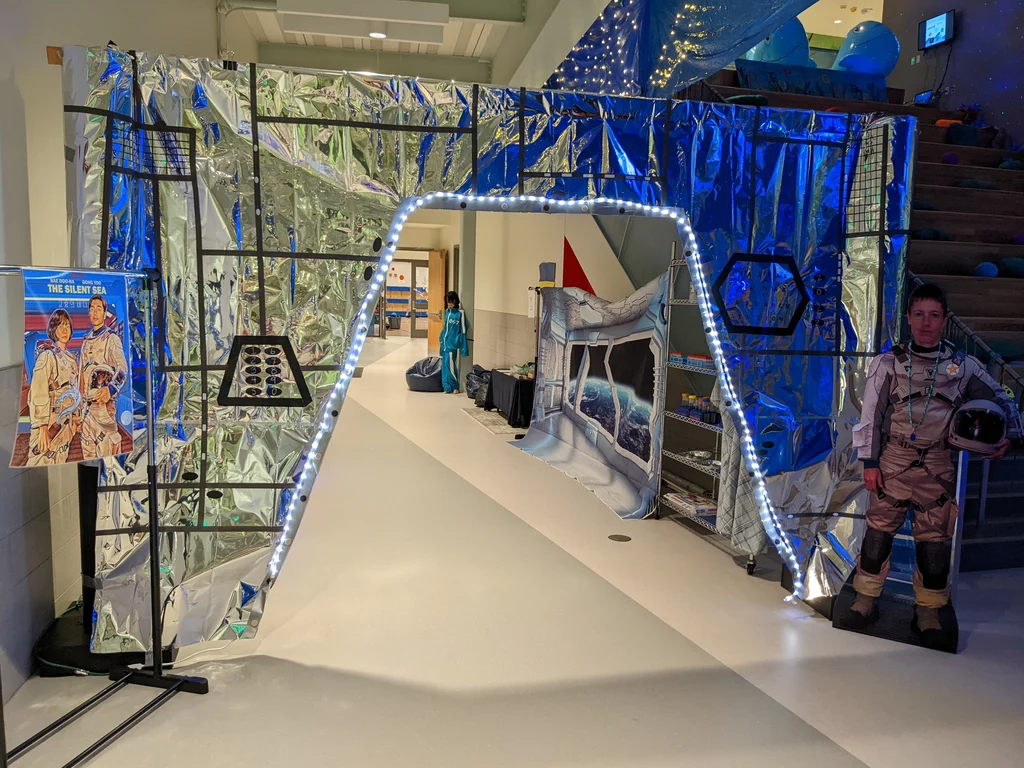 Space theme party with man as astronaut standing in front of a door displaying a sign Space theme party with man as astronaut standing in front of a door displaying a sign